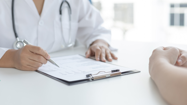 Lekarz pokazujący dokument medyczny pacjentowi podczas konsultacji przy biurku