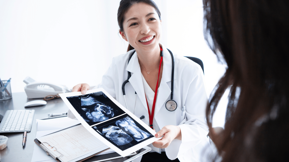 Lekarka ginekolog pokazuje pacjentce zdjęcia USG podczas konsultacji w gabinecie
